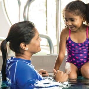 This image captures a cheerful and heartwarming scene of a swimming lesson.
