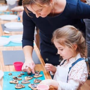 The image features a woman and a young girl engaged in a baking activity.