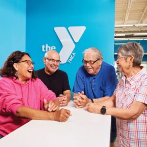 This image shows a group of four elderly people, two women and two men, gathered around a table,