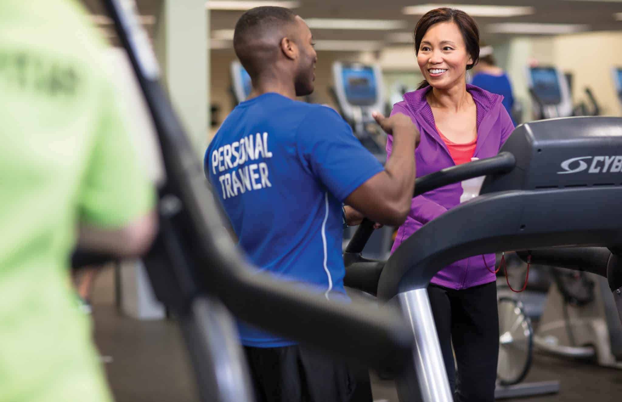Woman on treadmill speaking with her personal trainer
