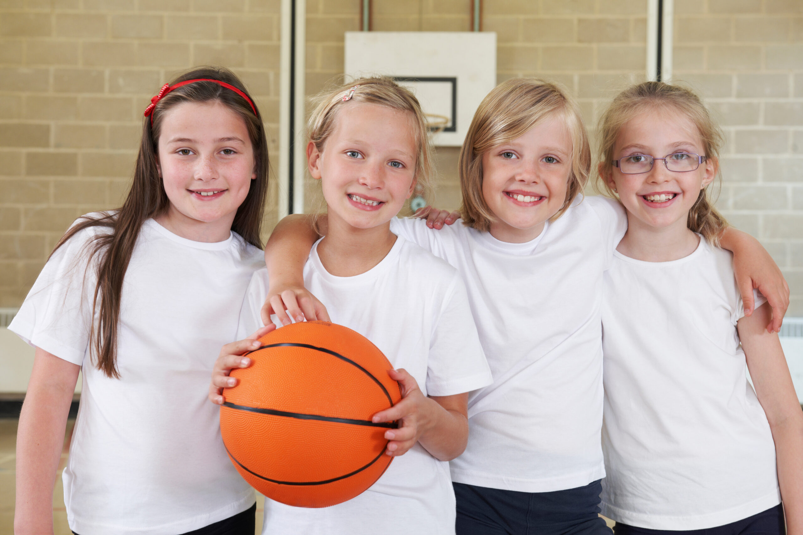 Female School Sports Team In Gym With Basketball