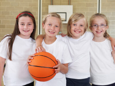 Female School Sports Team In Gym With Basketball
